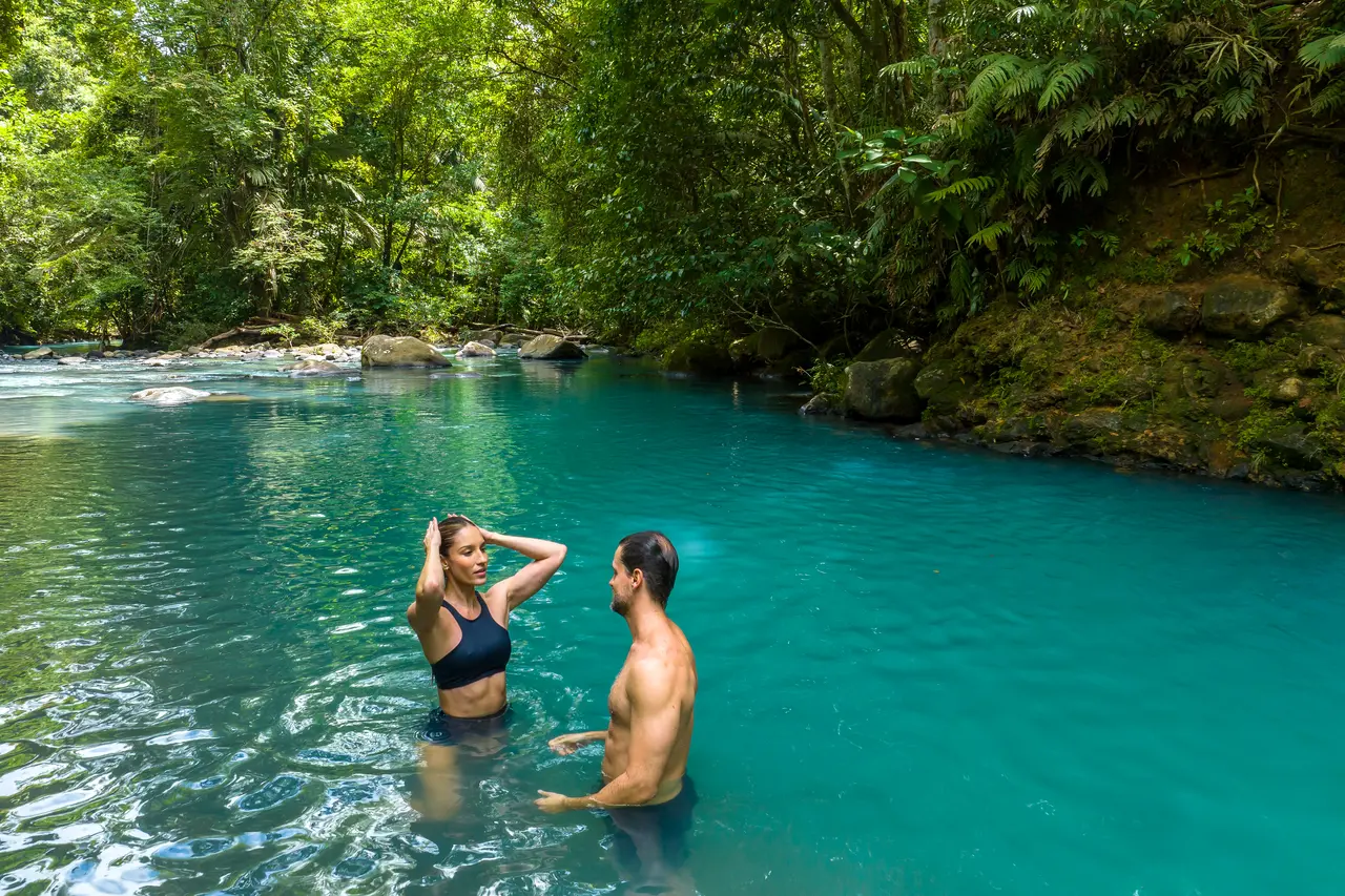 Guests swimming in the Río Celeste from the property